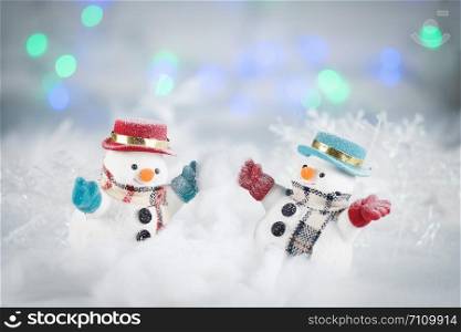 Two snowman playing snow and decorations on bokeh background, with copy space for season greeting. Merry Christmas or Happy New Year,