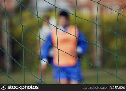 Two soccer players in front of a net