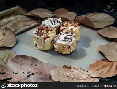 Two Soft Chocolate Buns topped with rich cream cheese frosting and Two Caramel Pecanbon topped with decadent caramel frosting and pecans on ceramic tray. The concept of delicious food, Selective Focus.