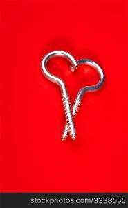Two spiral bolts laying in the form of heart on a red background