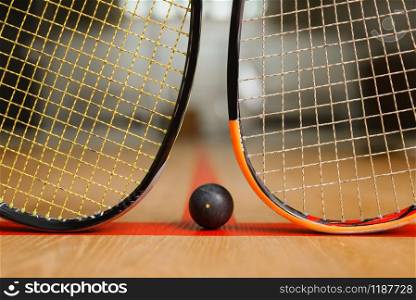 Two squash rackets and ball on court floor, nobody, game concept. Active sport hobby, fitness workout for healthy lifestyle. Two squash rackets and ball, game concept