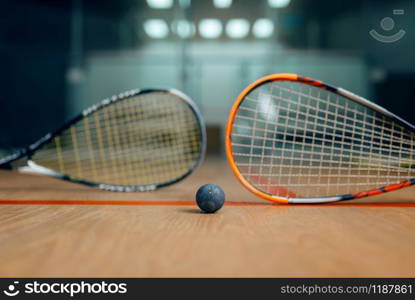 Two squash rackets and ball on court floor, nobody, game concept. Active sport hobby, fitness workout for healthy lifestyle. Two squash rackets and ball, game concept