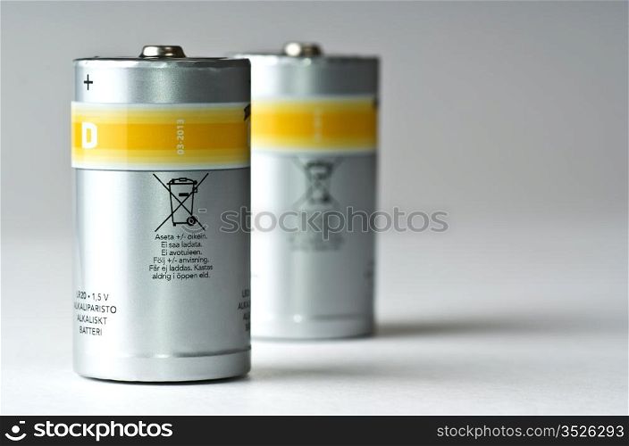 two standing D batteries, silvery with yellow strip