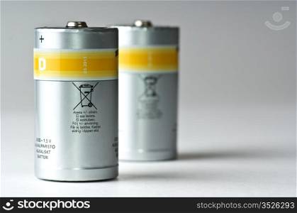 two standing D batteries, silvery with yellow strip