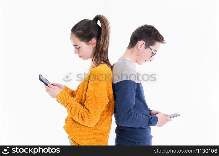 Two standing teenagers check their smartphones on a light background.. Two teenagers check their phones back to back
