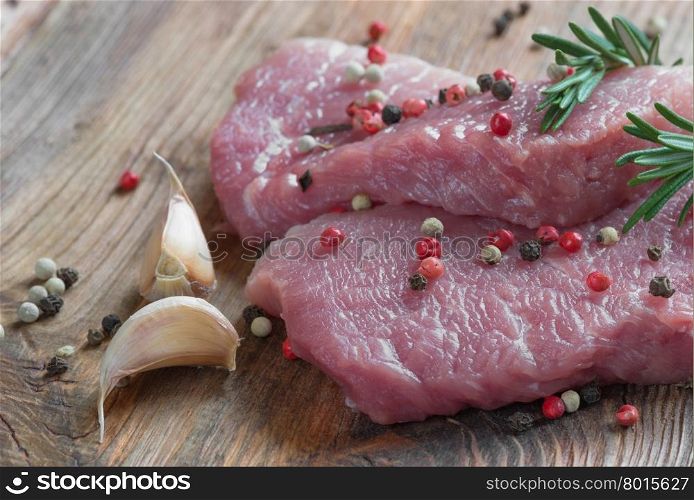 Two steaks from fresh organic meat and two sprigs of rosemary on an old wooden board close up