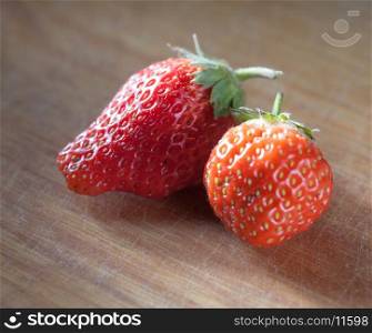 two strawberryes on the wooden plank
