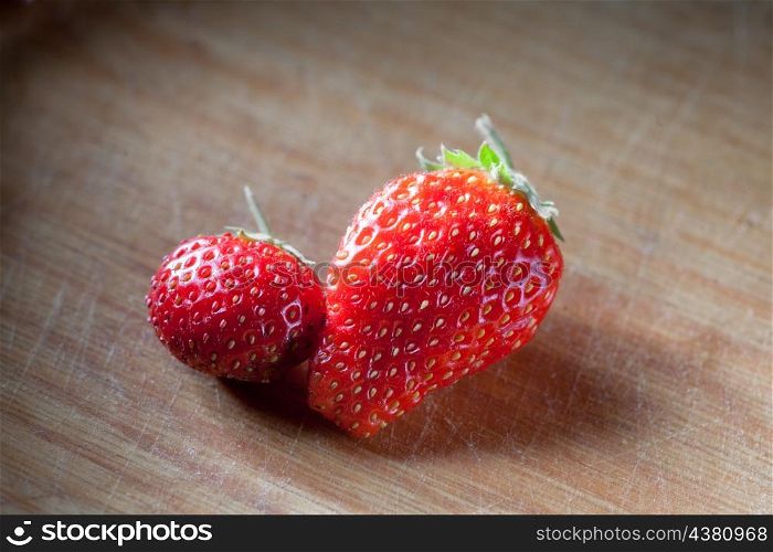 two strawberryes on the wooden plank