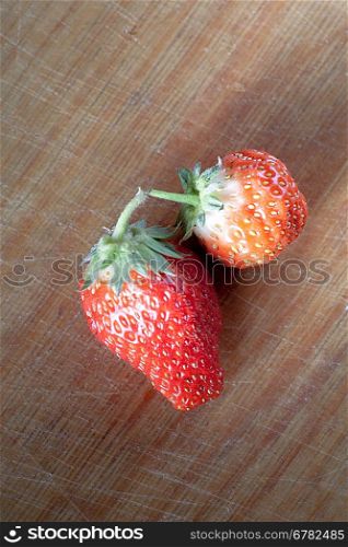 two strawberryes on the wooden plank, from above