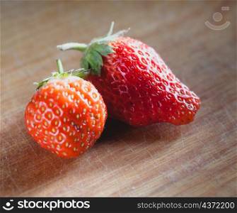 two strawberryes on the wooden plank, side view