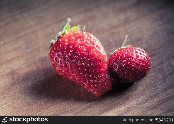 two strawberryes on the wooden plank, toned image