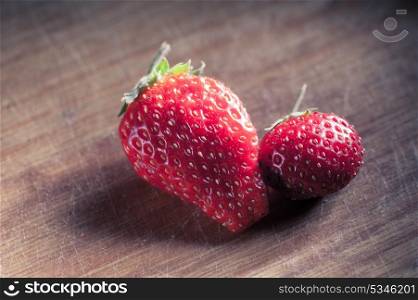 two strawberryes on the wooden plank, toned image