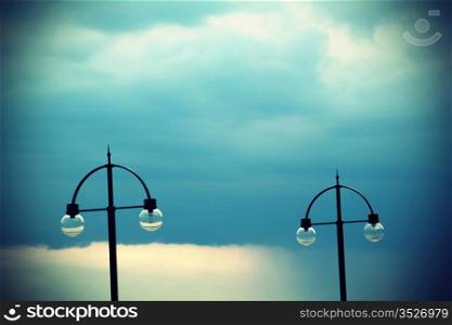 Two street lamps on evening sky
