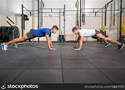 Two strong men doing push-ups in gym. High quality photo.. Two strong men doing push-ups in gym.