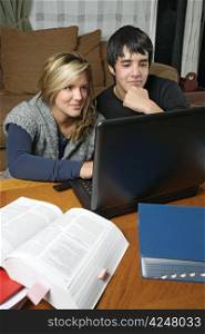 Two students and friends doing their homework using their laptop.
