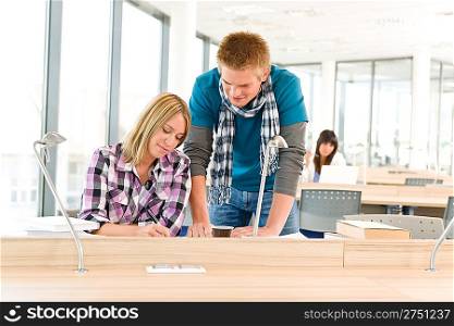 Two students at high school writing notes sitting in classroom