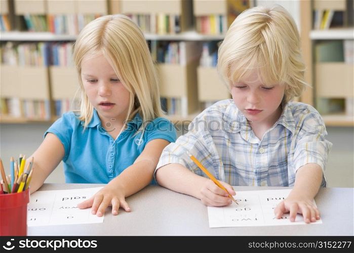 Two students in class learning letters