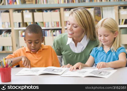 Two students in class reading with teacher