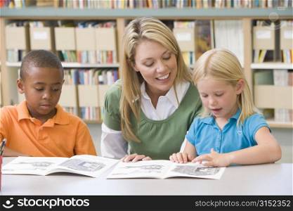 Two students in class reading with teacher