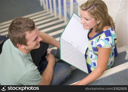 Two students sitting on staircase with notebooks (selective focus)