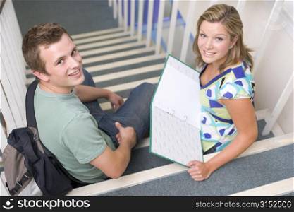 Two students sitting on staircase with notebooks (selective focus)