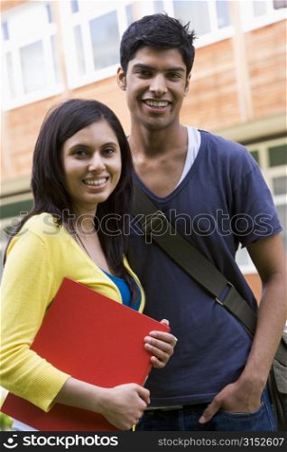 Two students standing outdoors smiling