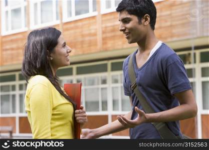 Two students standing outdoors smiling and talking