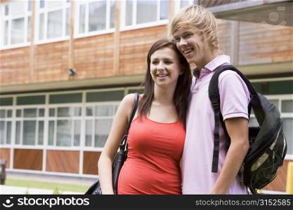 Two students standing outdoors with arms around waists smiling