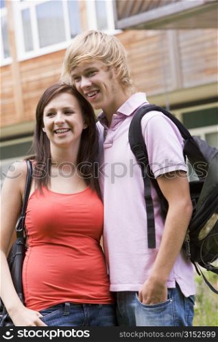 Two students standing outdoors with arms around waists smiling