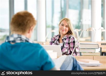 Two students with books and laptop in classroom studying
