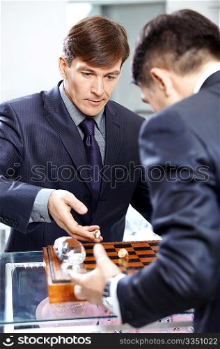Two successful businessmen play a chessboard