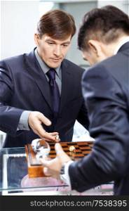 Two successful businessmen play a chessboard