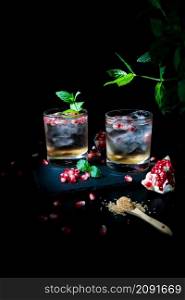 Two summer drinks with pomgranate, mint and some sugar. black background