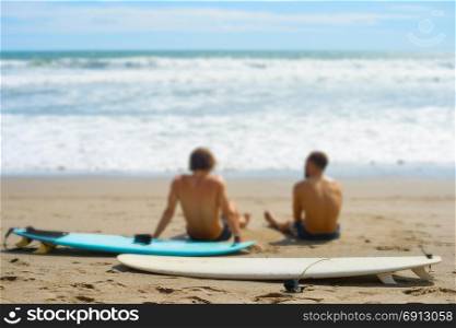 Two surfers with surfboards resting on the beach. Selective focus on the surfboard. Bali island, Indonesia