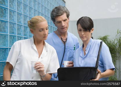 Two surgeons and a female doctor discussing a medical report