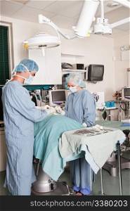 Two surgeons performing operation, surgical instruments in foreground