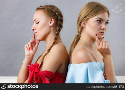 Two suspicious female friends having thinking face expressions, being angry at each other.. Two suspicious women