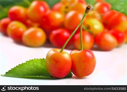 Two sweet cherries crosswise on white with fruit background
