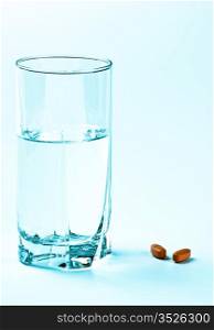 two tablets and glass of water on blue background