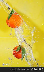 two tangerines and water splashes on yellow, close up