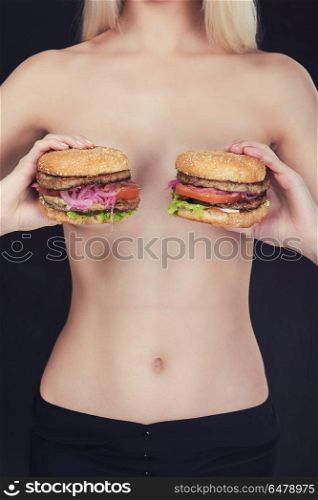 Two tasty burgers. Young naked woman keep in her hands two tasty burgers.
