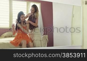 Two teen girlfriends in bedroom getting dressed for a night out