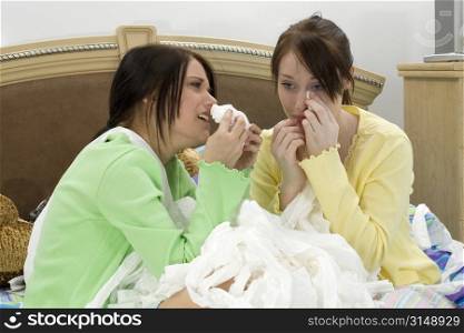 Two teen girls crying into a huge pile of toliet tissue.