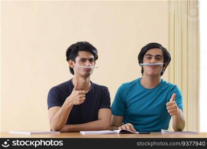 Two teenage boys having fun and gesturing while studying together at home