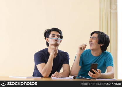 Two teenage boys having fun while studying together at home