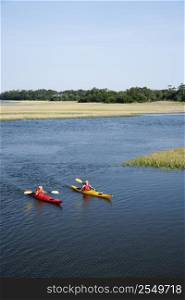 Two teenage boys kayaking through marshland on Bald Head Island, North Carolina.