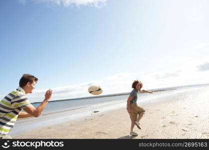 Two Teenage Boys Playing Rugby On Beach Together