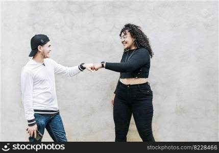 Two teenage friends bumping their fists. A guy and teenage girl shaking fists at each other, close up of two funny friends bumping fists in a friendly way