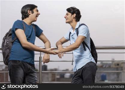 Two teenage friends talking while standing together by railing