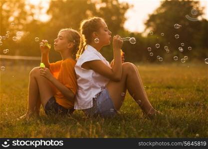 Two teenage girls have fun in the park. Two friends outdoor. Summer people doing bubbles